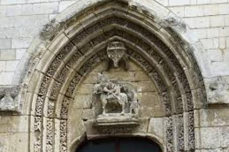 Detail of the main entrance of a church decorated with a pointed arch and a statue