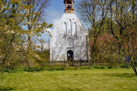 Simple white church with a wooden bell tower in the countryside.