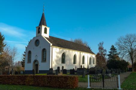 13th century white church placed next to a graveyard.