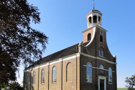 Simple brick church with a white turret in a field