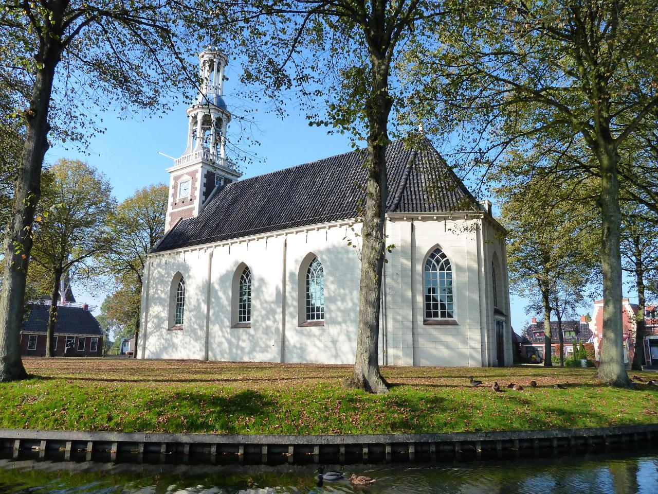 White church with black roof in a park