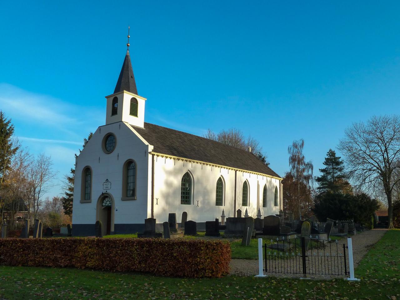 13th century white church placed next to a graveyard.