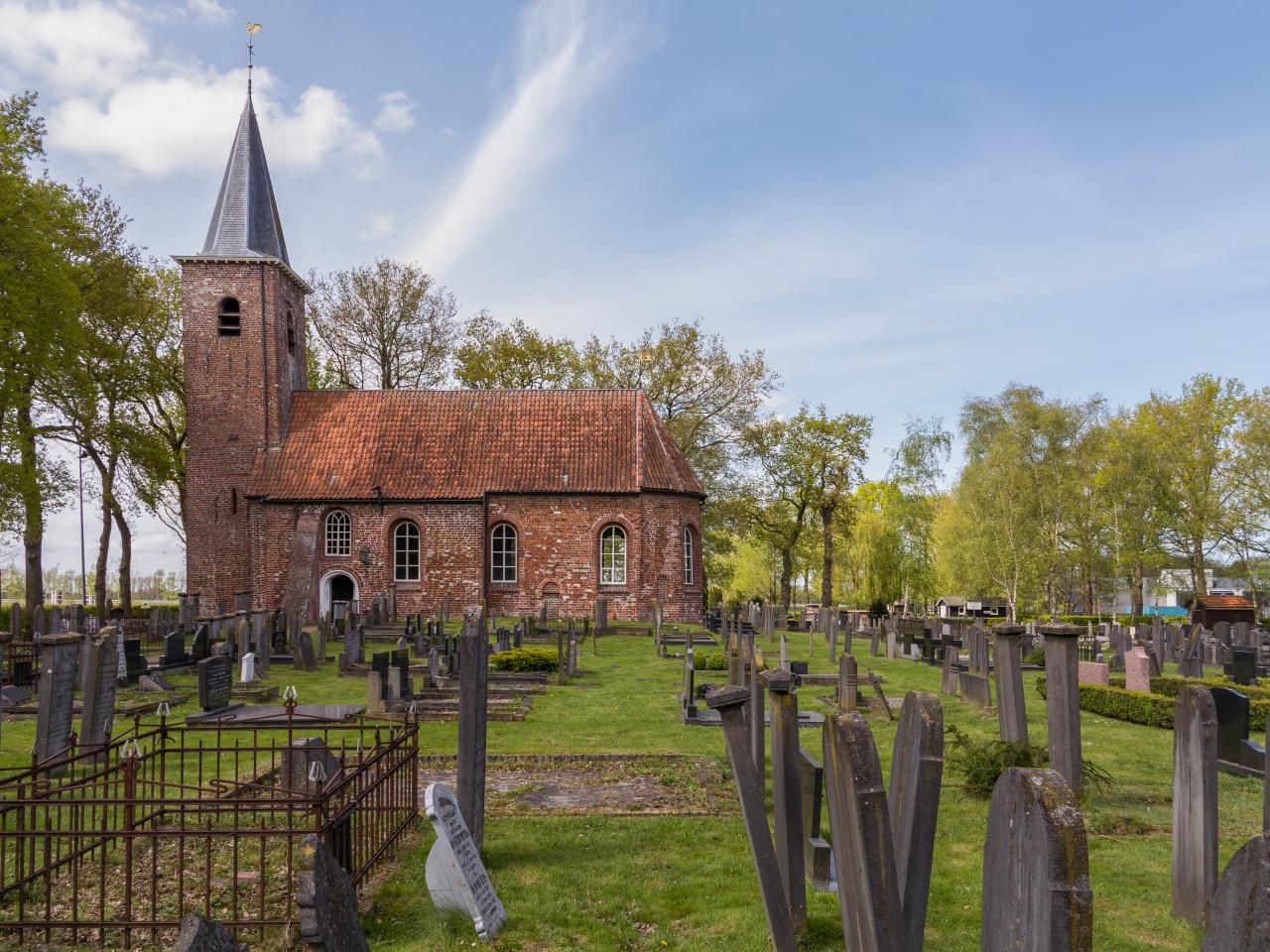 Brick church  with annexed bell tower and large graveyard in a field