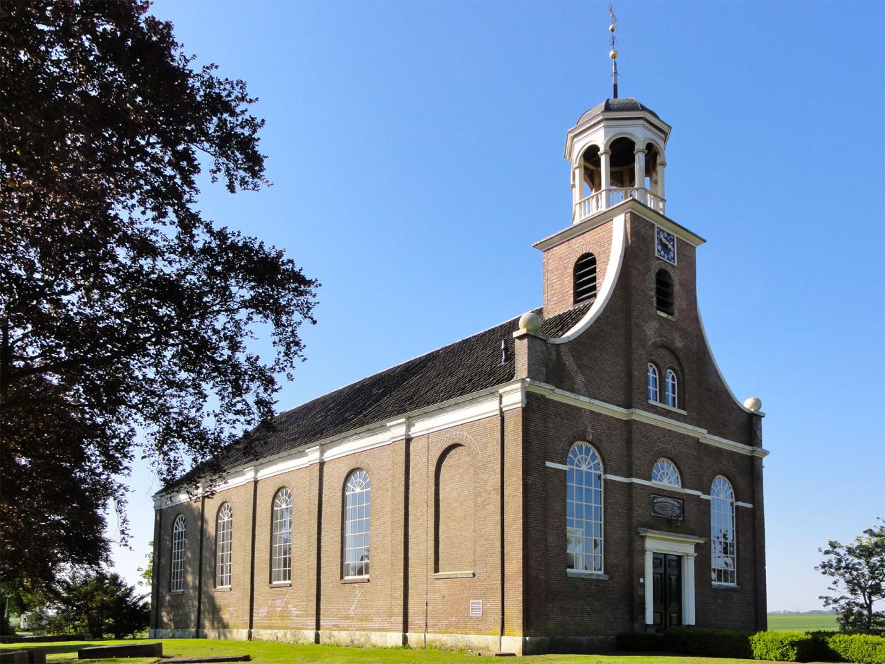 Simple brick church with a white turret in a field