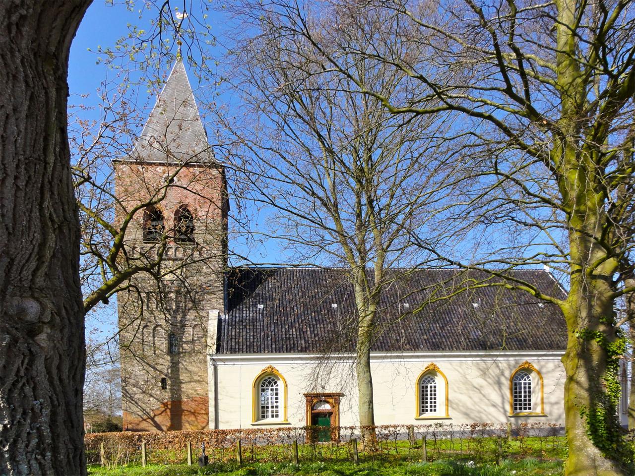 simple church with yellow plaster details and a brick bell tower