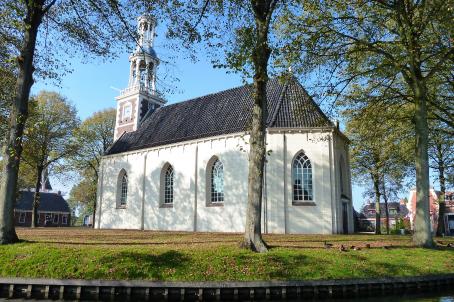 White church with black roof in a park
