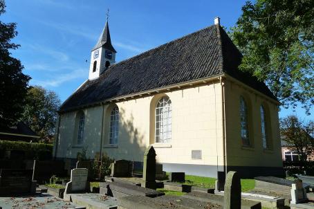 Simple white church with a black roof next to a graveyard.