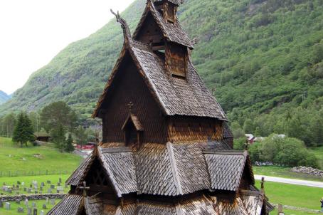 Stave church in front of a green hill
