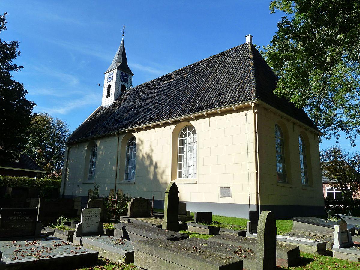 Simple white church with a black roof next to a graveyard.